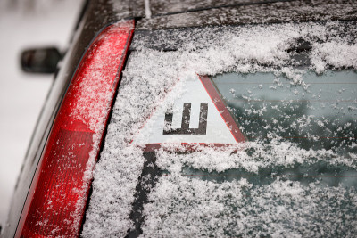 这是汽车和街道上的第一场雪。警示牌-尖钉-用于冬季轮胎带尖钉的汽车。镶嵌轮胎的季节。冬天在结冰的道路