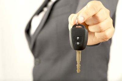 推销员拿着车钥匙在陈列室以低利率提供给顾客。特别的促销活动