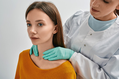 内分泌科医师触诊检查成年女性患者甲状腺。女性甲状腺肿大，激素分泌不正常