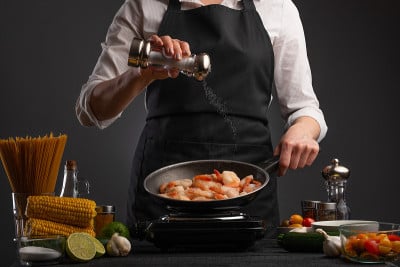 专业厨师以蔬菜为背景，将虾煎炸、腌制。海鲜和健康食品。