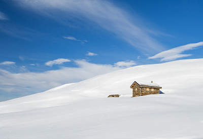 全景横跨积雪覆盖的山坡上的高山小屋