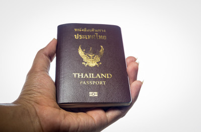 男子手持泰国护照孤立白色背景。泰国旅游概念。