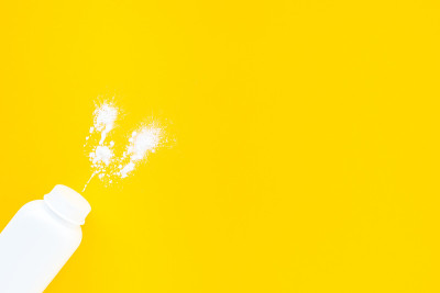 White baby powder jar on yellow background, flat l