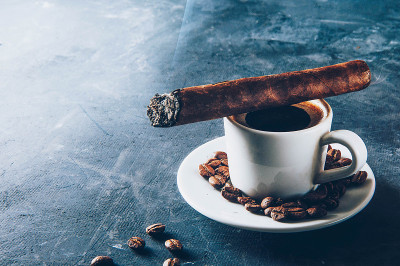 一杯咖啡，咖啡豆，烟灰缸和雪茄在黑暗的背景