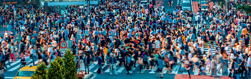 在日本东京涩谷，人们和车辆穿过著名的混乱十字路口