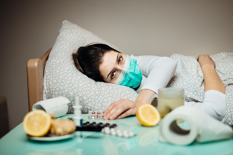 患病妇女在家隔离床上自我隔离。重症肺炎的疾病。患有冠状病毒病症状的戴口罩流感患者。Covid-19攻