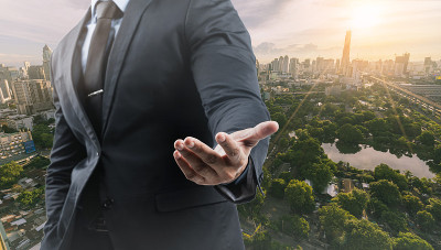 商业和可持续城市，成功商人西装和手，公园在城市的背景。