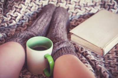 女人的腿在羊毛袜和一杯茶