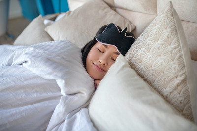 年轻的黑发女孩戴着睡眠面罩，安睡在床上
