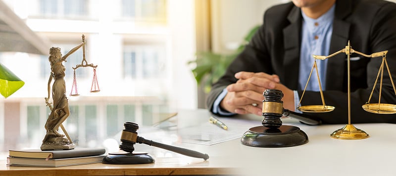 律师咨询法律男法官在法庭上的木桌上用锤子和天平和工作在办公室法律的概念，咨询和正义