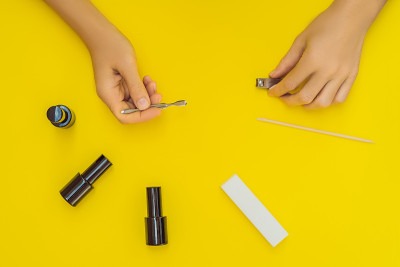 女人的手。俯视图美丽光滑的女人的手与专业指甲护理工具美甲在黄色的背景。健康女性指甲与黄色指甲油的特写
