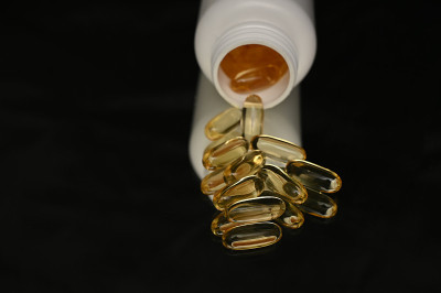 鱼油胶囊含有omega - 3和维生素D在一个塑料瓶上木质质地，健康的饮食理念