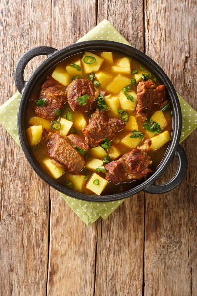 美味的Aloo Gosht食谱羊肉咖喱土豆特写在平底锅。垂直的俯视图