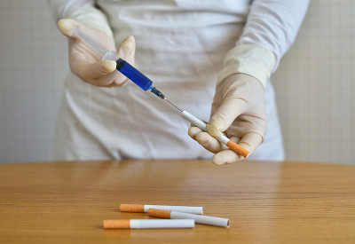 一个拿着注射器和香烟的科学家。向香烟中注入化学物质