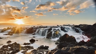 日落时的毛伊岛小海滩——冲浪沙和熔岩上的太阳