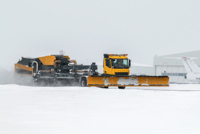 在一场严重的暴风雪中，机场吹雪机正在清理机场飞机库附近的区域
