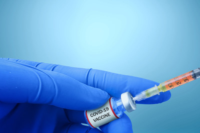 卫生工作者手拿注射器和covid - 19疫苗的手套