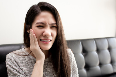 亚洲美女摸她的脸颊和牙痛和有超敏感的牙齿。