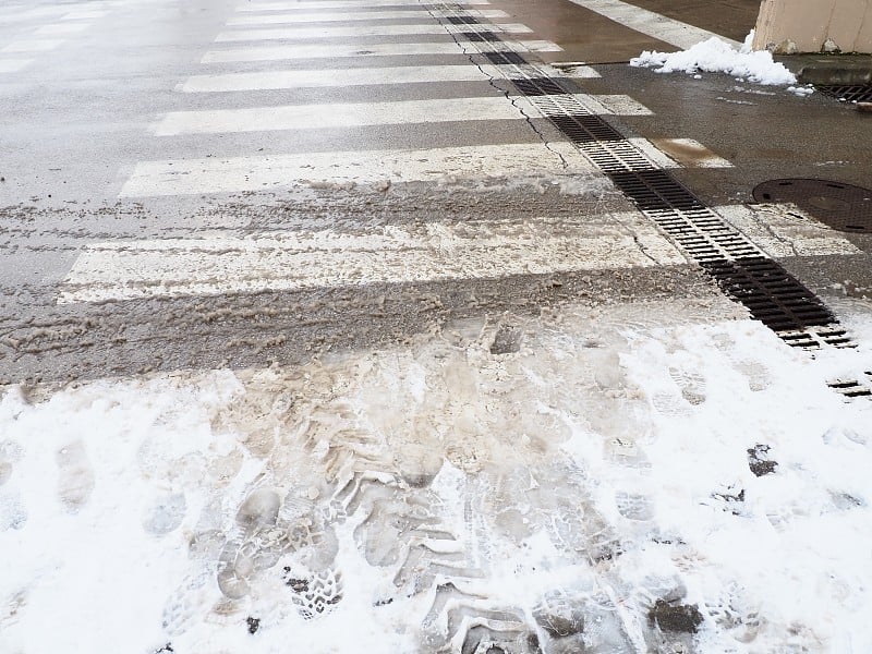 行人十字路口的雪、冰、雪泥和冬天的泥。气温在零度左右。困难的驾驶环境。汽车制动距离。交通法规。基础设