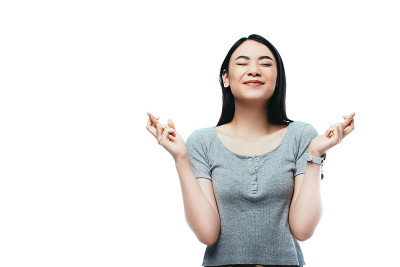 亚洲女孩闭着眼睛，交叉手指孤立在白色