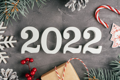2022年新年快乐。白色的数字2022躺在灰色的不平整的混凝土表面和圣诞树的树枝。俯视图