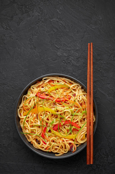 辣椒蒜味客家面在黑色的碗里，在黑色的石板桌上。印中素食菜肴。印度蔬菜面条。典型的亚洲餐。副本的空间。