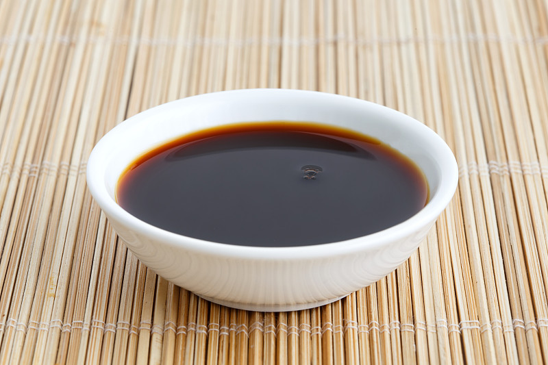 酱油在白色陶瓷碗孤立在竹席上。