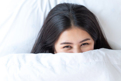 美丽的少年睁开眼睛盖着她的脸与毛毯