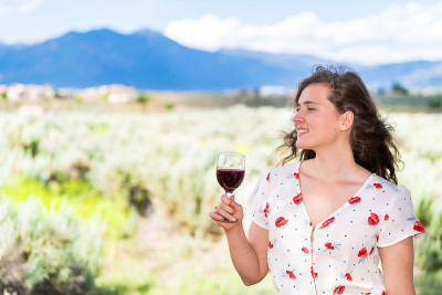 女人品尝红酒从Taos Sangre de Cristo山从Ranchos de Taos山谷背景后