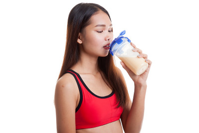 美丽的亚洲健康女孩喝乳清蛋白。