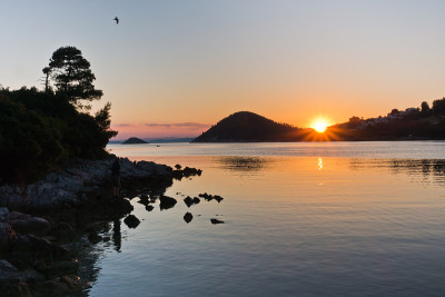 斯科佩洛斯岛，日落时全景海湾的岩石海岸和平静的海水
