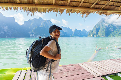 泰国女人穿着背包微笑与湖和山的背景