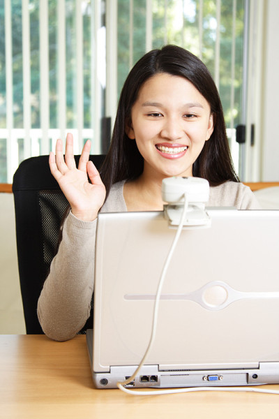 女商人对着笔记本电脑上的摄像头挥挥手