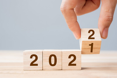 商人手持木质立方体与翻转块2021年至2022年的文本在桌子的背景。决议，策略，解决方案，目标，业务