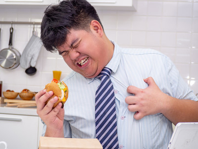 一名亚洲男子在吃东西时感到心脏疼痛。心脏病发作，胸痛的男人。