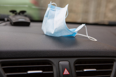 Protective medical face mask on the dashboard in t