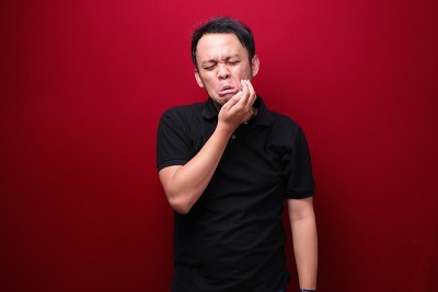 亚洲年轻男子牙齿问题与受伤的情绪穿黑衬衫。