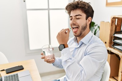 年轻的西班牙商人微笑着开心地在办公室服药。