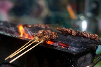 小贩在街头小吃市场用木炭烧烤沙嗲肉