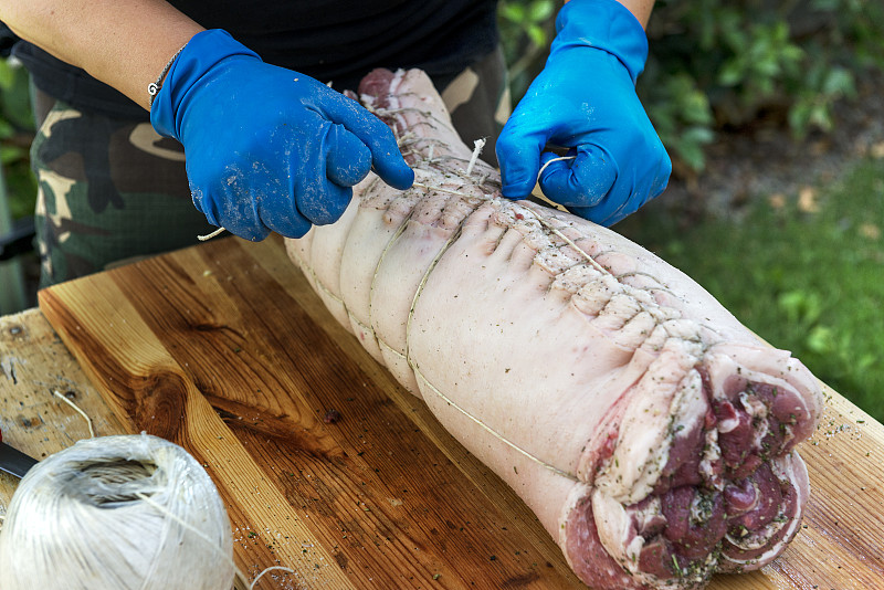 屠夫把肉卷起来做成烤猪肉