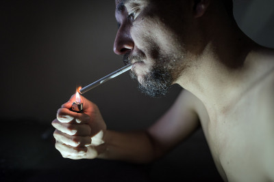 一个年轻人在暗室里抽烟。