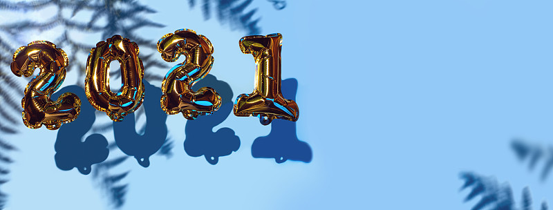 2021年圣诞金球。蓝色背景上的阴影。新年的概念。聚会装饰、周年纪念标志、节日庆典、嘉年华。