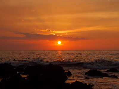 夕阳下的海洋与熔岩岩石的Holoholokai海滩在前景