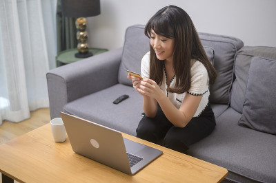 年轻的美女正在家里用信用卡在网上购物，电商概念