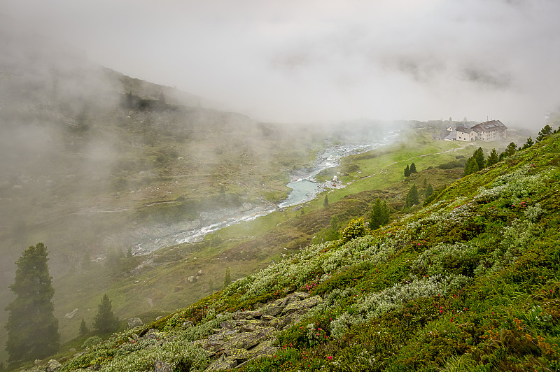 在山上，俯瞰下方雾蒙蒙的草地，可以看到奥地利齐勒塔尔(Zillertal)一条流淌的河流。