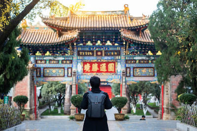 快乐的男人旅行者与毛衣和背包在圆通寺，佛教寺庙在昆明。中国云南昆明的地标和旅游景点。亚洲旅游的概念