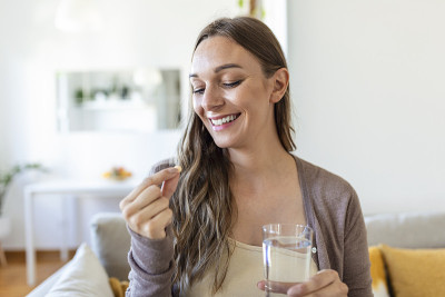 幸福的女人捧着药丸一杯水，每天服用药物维生素D、欧米茄3补充剂，皮肤发甲强身和美容，药物为保健理念