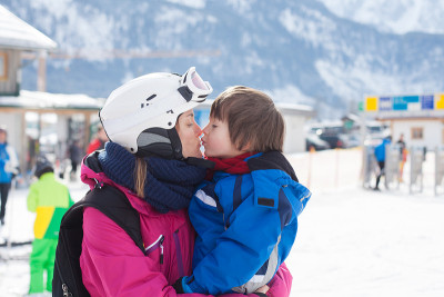 美丽年轻的妈妈和她蹒跚学步的儿子，在山上滑雪