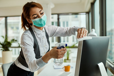 女商人戴着口罩在办公室清理电脑。
