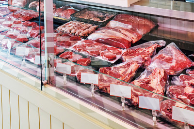 在肉店的冷藏柜里挑选新鲜的小牛肉